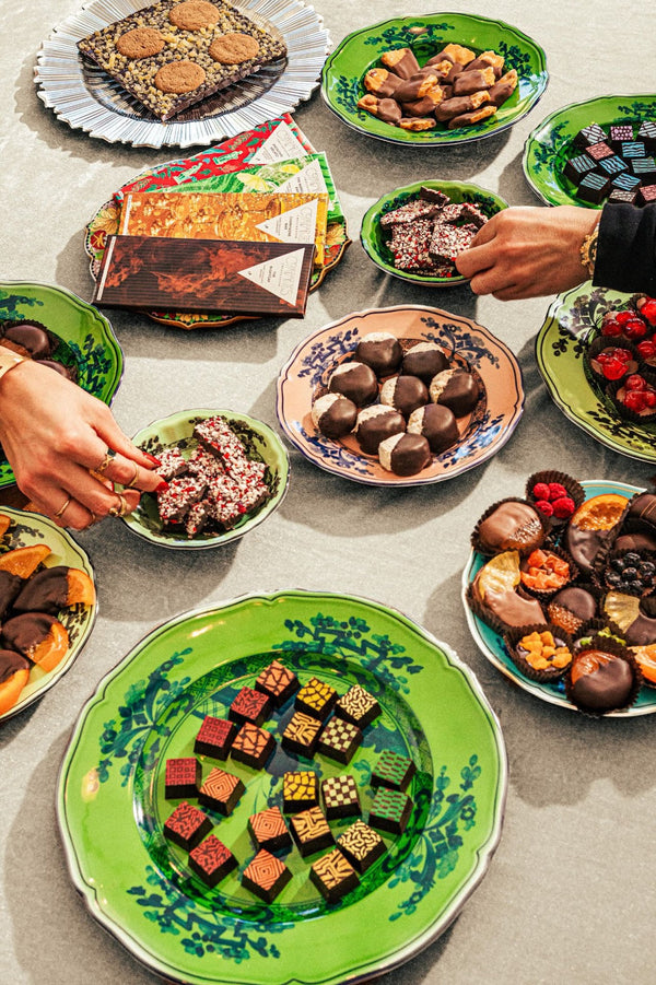 Hands grabbing for chocolate truffles and fruits on table — Compartes