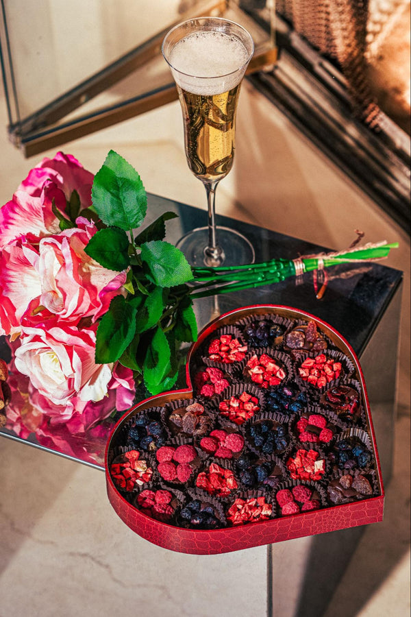 Unique Valentine’s Day gift featuring a heart-shaped box of gourmet chocolate truffles paired with champagne and roses