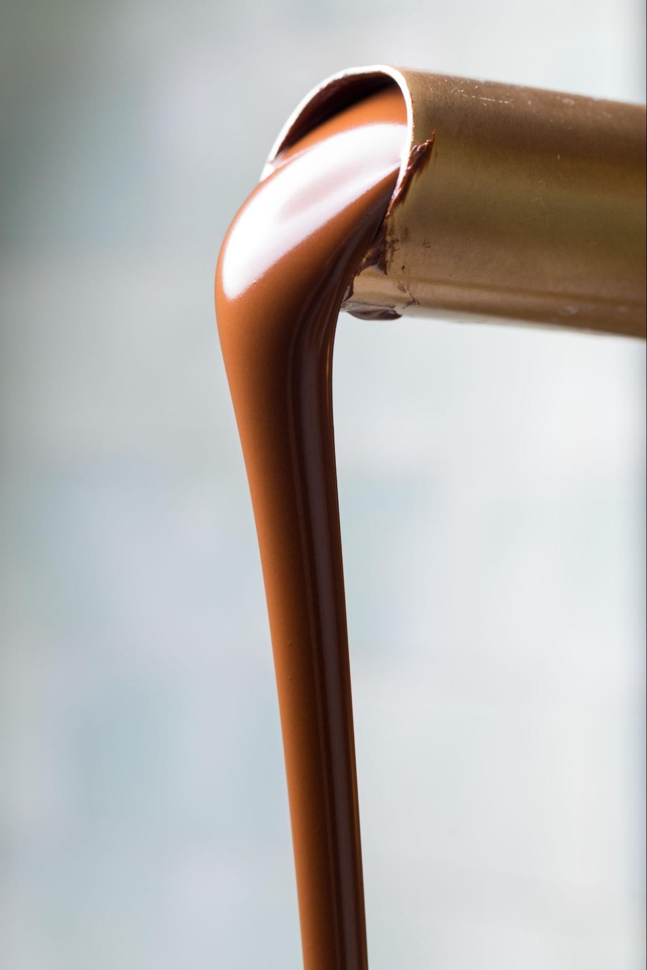 Smooth milk chocolate pouring out of spout —Compartés