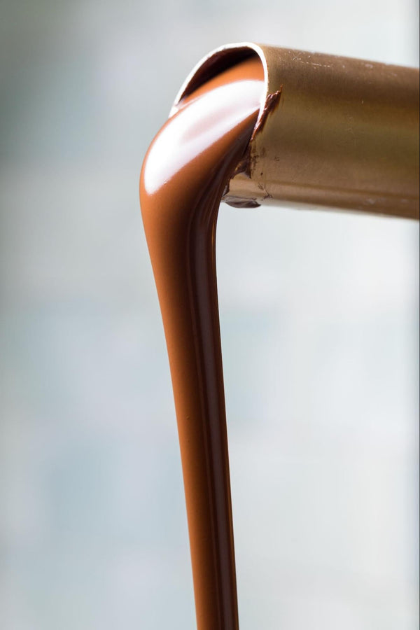 Smooth milk chocolate pouring out of spout —Compartés