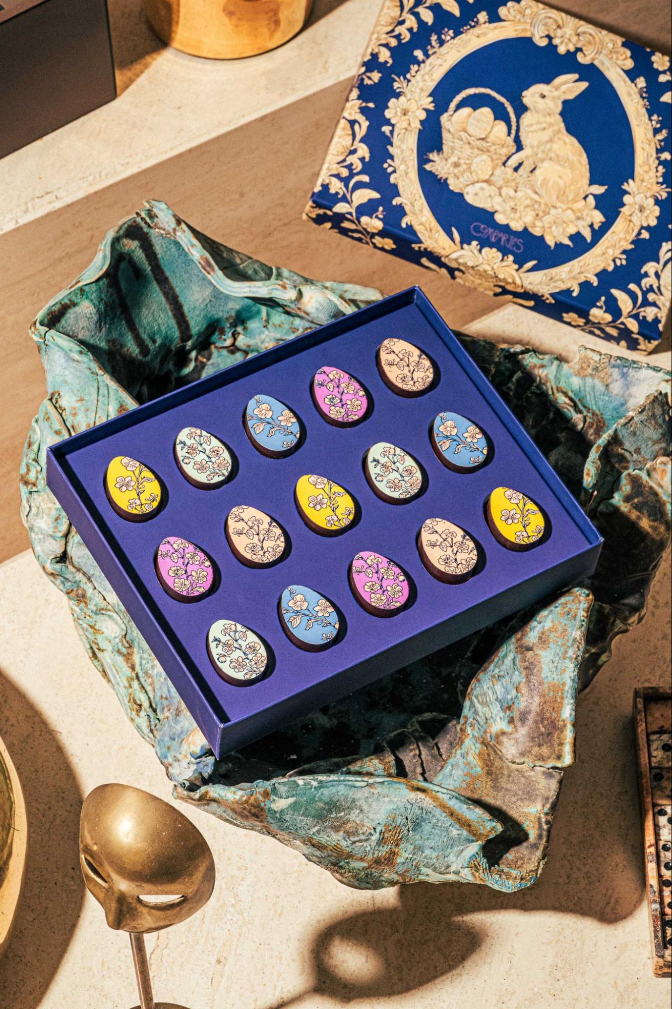 Hand-decorated chocolate eggs arranged in a blue Easter gift box