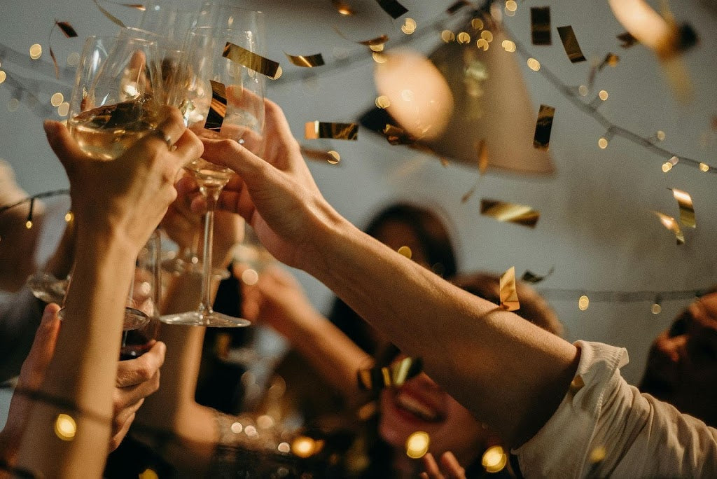 People toasting with wine glasses at a party – Compartes