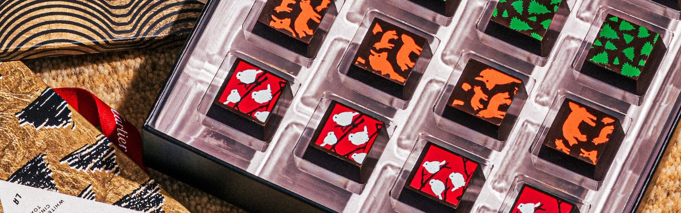 An open box of custom chocolate truffle boxes, with the Luis Vitton, Facebook, and Instagram logos on the chocolates.