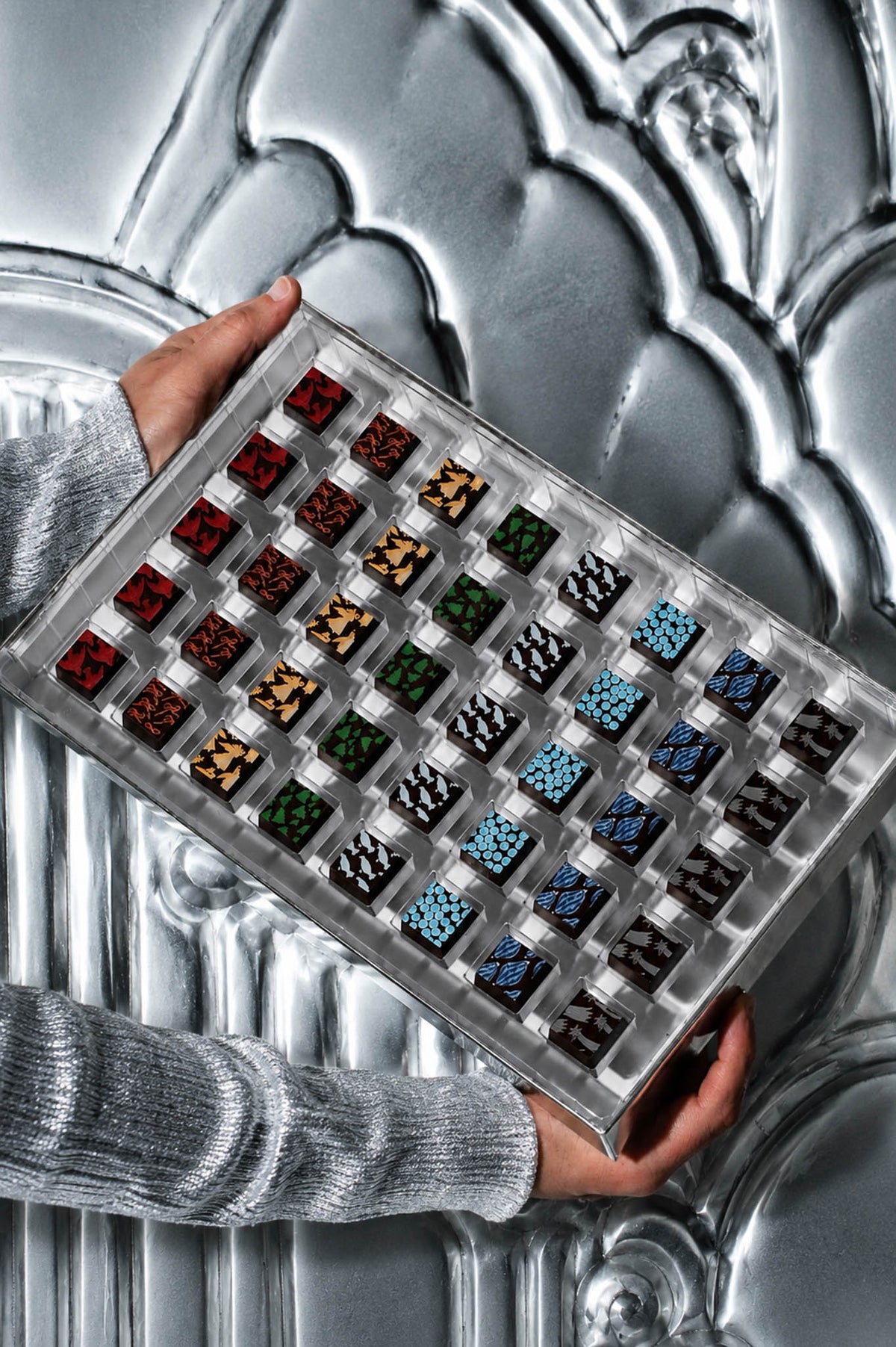 Assorted Christmas Chocolates in Gift Box By Compartes Chocolatier Los Angeles. Beautiful printed chocolates in holiday christmas patterns in a silver gift box.