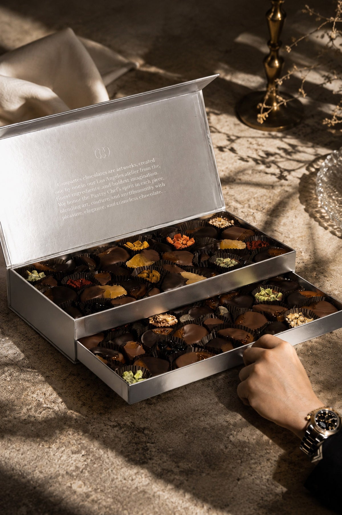 A luxury chocolate gift box filled with assorted gourmet chocolates and chocolate dipped fruits. Mixed premium dark and milk chocolate covered items in a designer silver gift box.