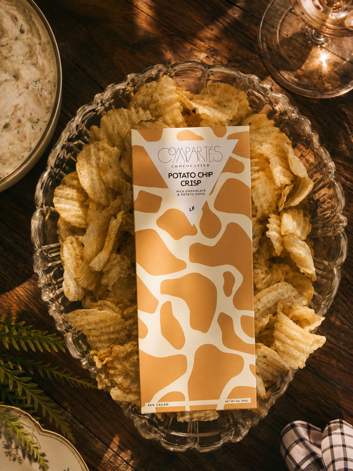 Potato Chip Milk Chocolate Bar by Compartes Chocolatier LA handmade potato chips in premium milk chocolate in a bed of potatoe chips.