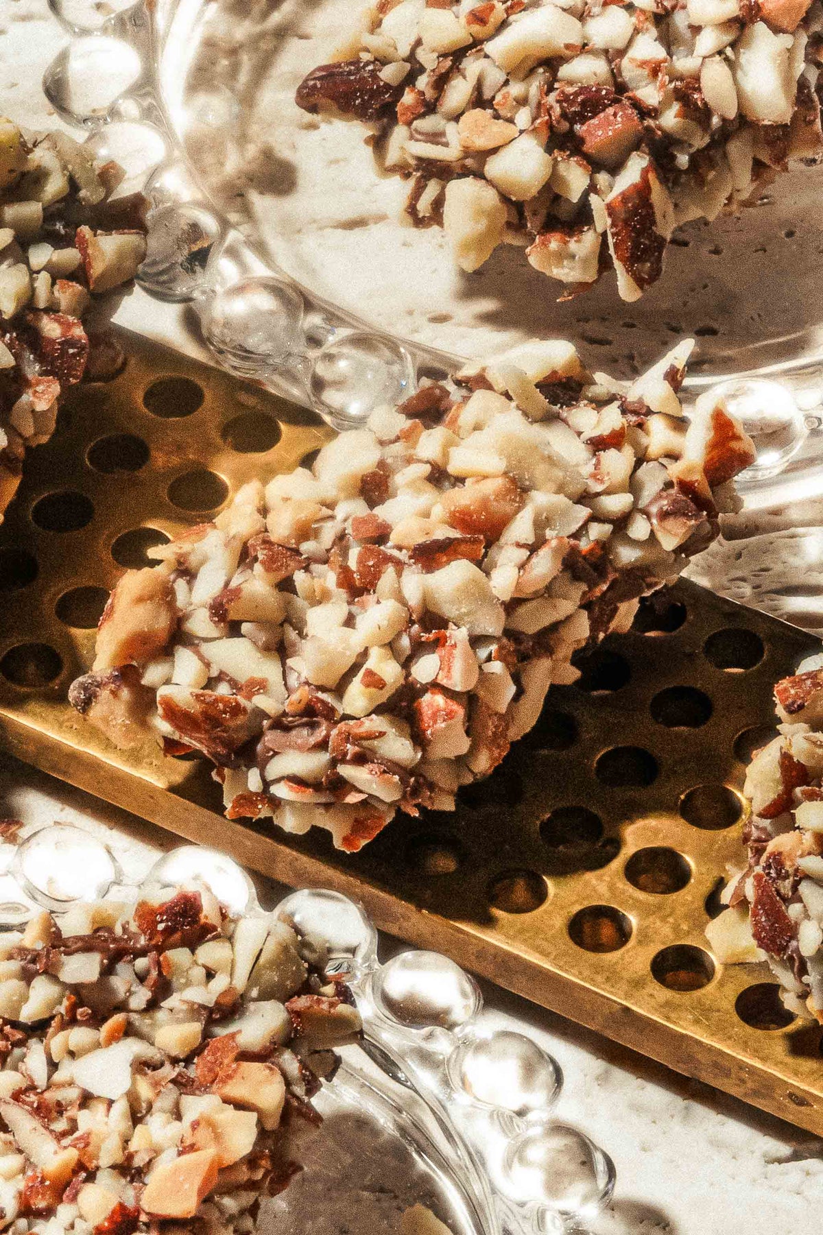 Compartes gourmet chocolate toffee covered in chopped almonds on a gold tray