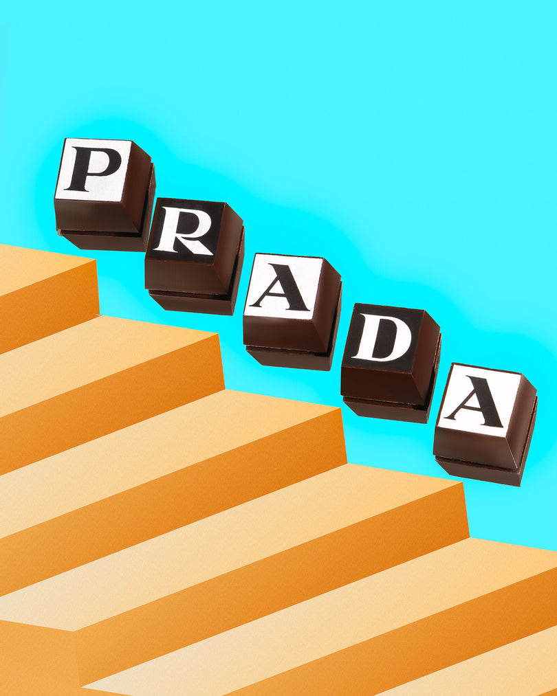 Prada branded chocolates on a blue background with orange, 3D rectangles along the bottom
