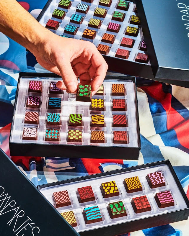 Multiple open colorful truffle boxes with hand — Compartes