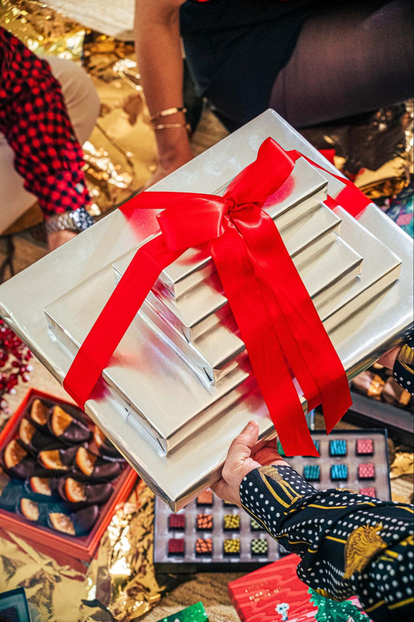 Stack of gift boxes in red ribbon above Compartés chocolate assortments