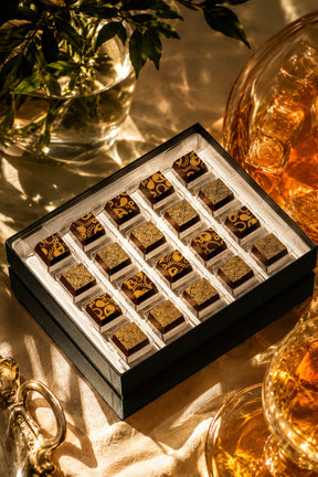 A boxed chocolate assortment of boozy chocolates with dark chocolate champagne truffles and whiskey truffles. Premium gourmet chocolates in a luxury gift box by Compartes Chocolatier.