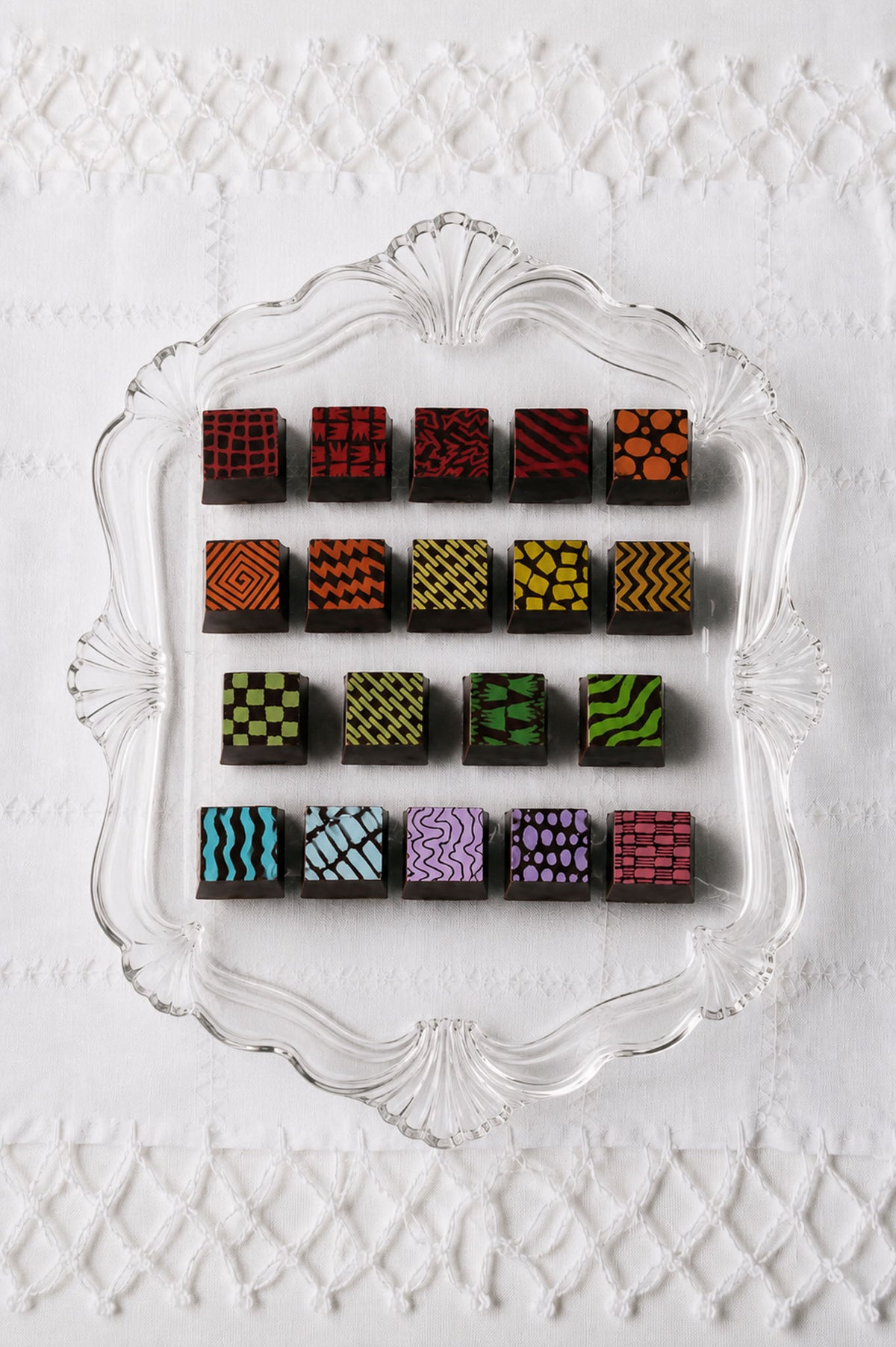 Gourmet Chocolate Truffles in colorful patterned chocolates prints by Compartes Chocolatier Los Angeles. Chocolate art designer chocolates on a white background.