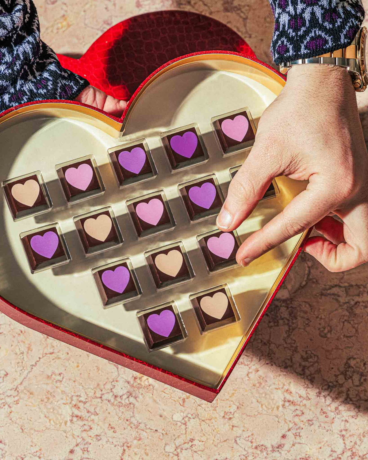 Vegan Valentine's Chocolate box with heart chocolate truffles and a hand picking one up