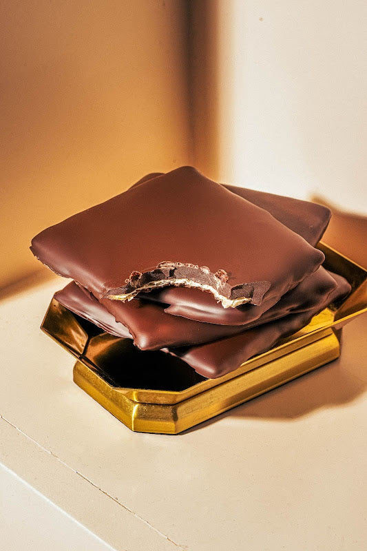 Tom Ford branded chocolates by Compartés on a blue, glass-like background