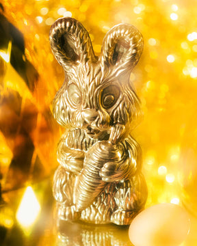 Gold chocolate bunny in front of a golden background	